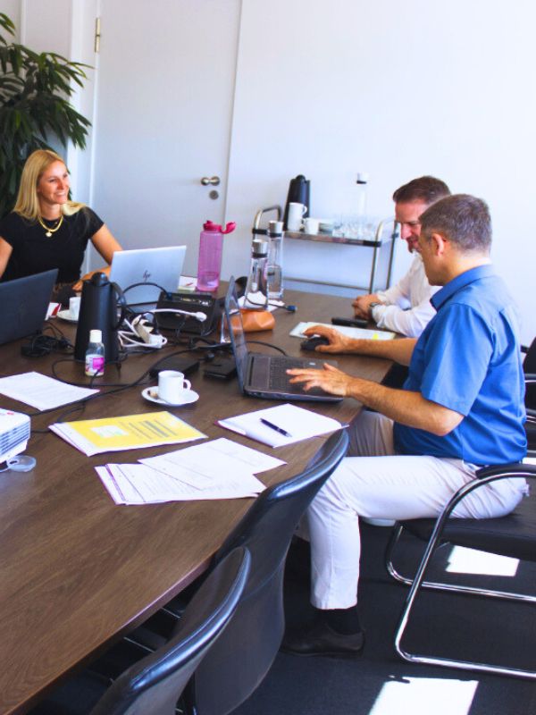 Mitarbeitende arbeiten im Besprechungsraum gemeinsam am internen Qualitätsmanagementsystem und stimmen Leistungs-, Service- und Kontaktqualität an Prozessschnittstellen ab.