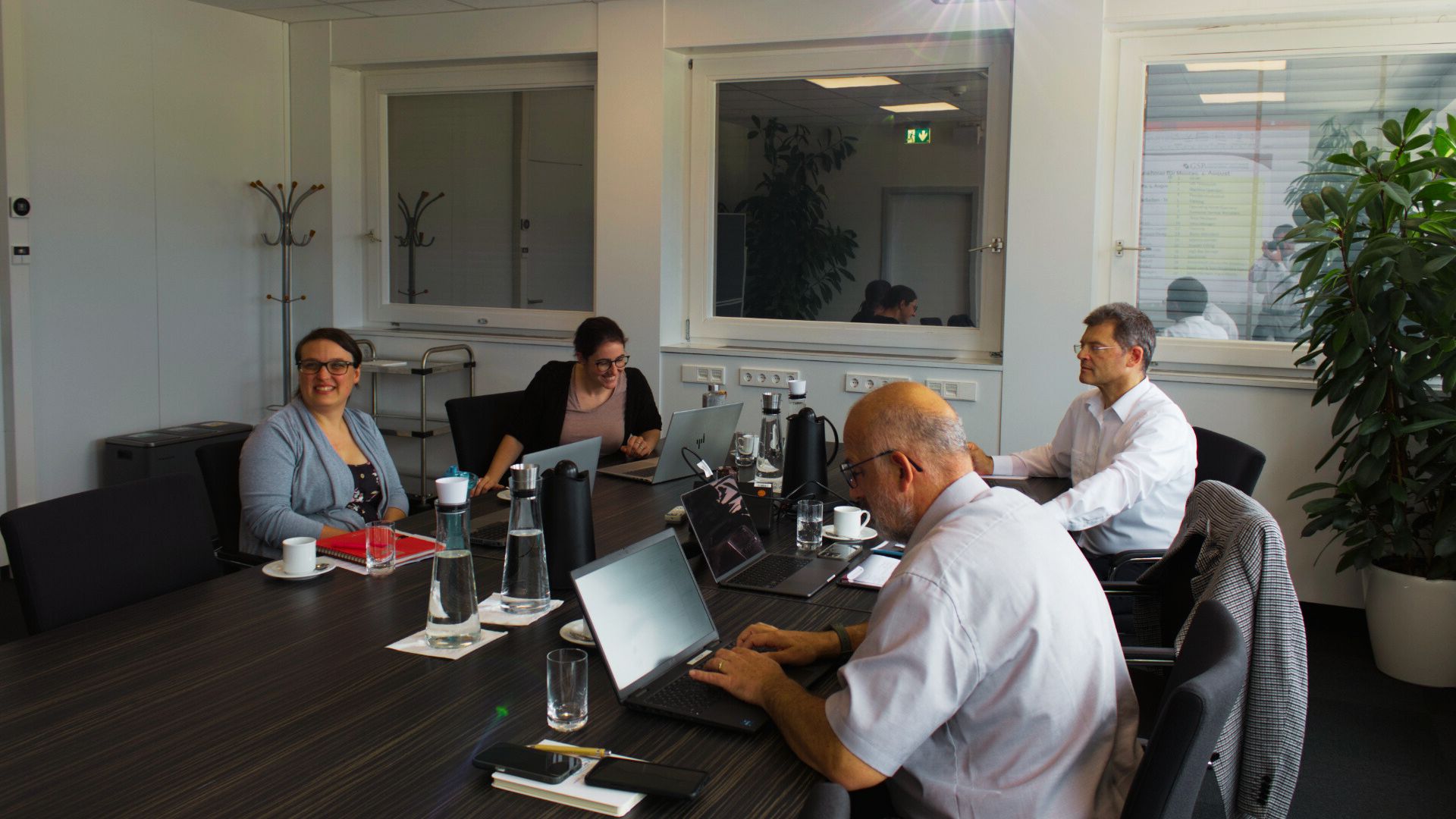 Team-Workshop zum internen Qualitätsmanagementsystem: Mitarbeitende arbeiten an Laptops im Besprechungsraum und optimieren interne Schnittstellen und Prozesse.