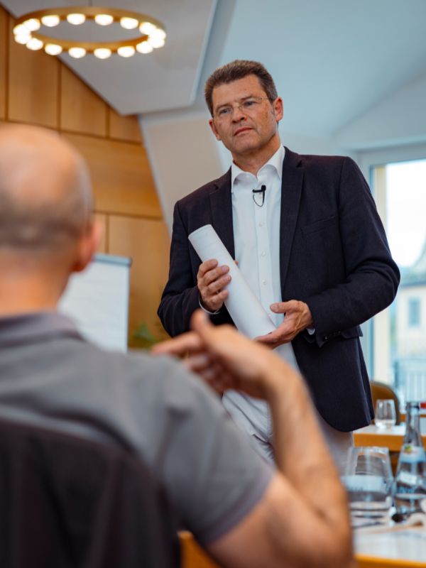 Führungskraft erläutert Szenariomanagement zur Steuerung von Restrukturierung und strategischer Organisationsänderung in einer Managementbesprechung.